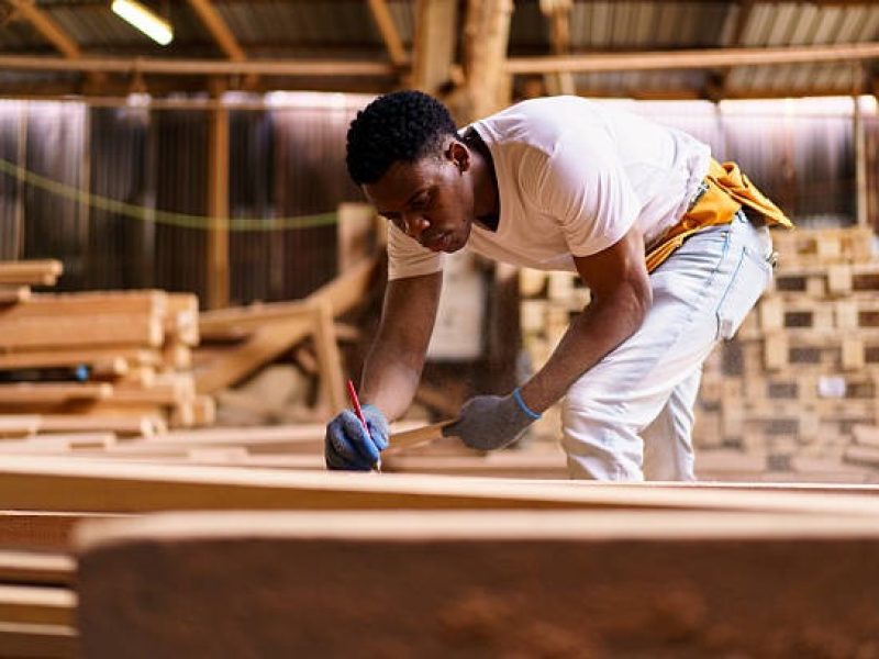 imgi_9_black-carpenter-working-in-woodworking-factory-carefully-inspecting-a-wooden-plank-after